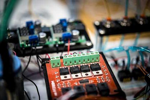 orange circuit board wired to another circuit board